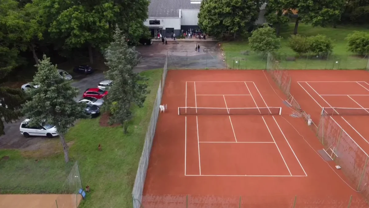 Court en terre battue vu du ciel, entouré de verdure