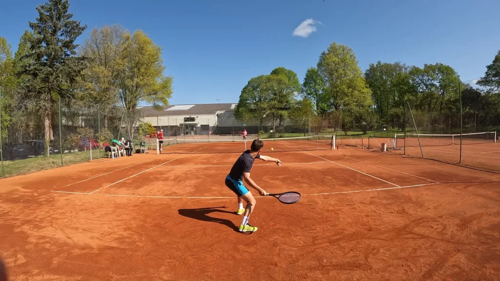 Joueur au service sur un court extérieur en terre battue du Country Club Nantais