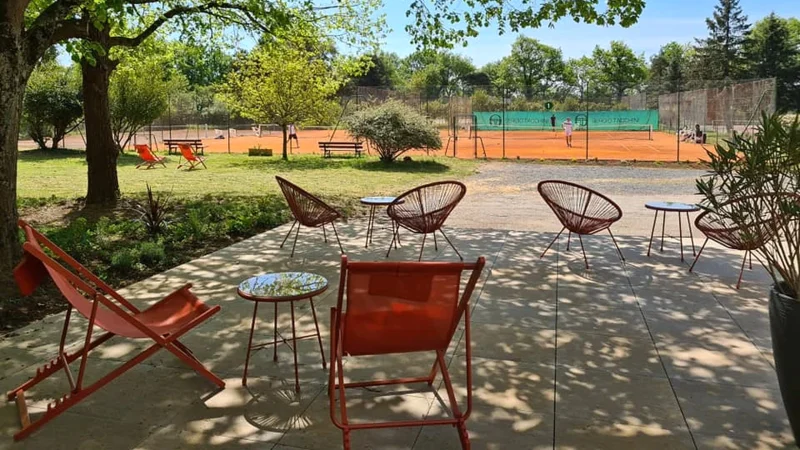 Terrasse ombragée du Country Club Nantais avec transats, face aux courts en terre battue